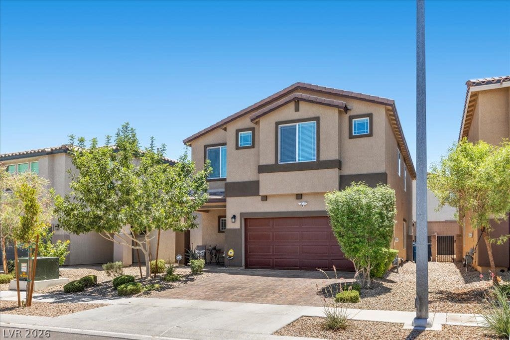 A well-maintained facade with a two-car garage and mature landscaping welcomes residents.