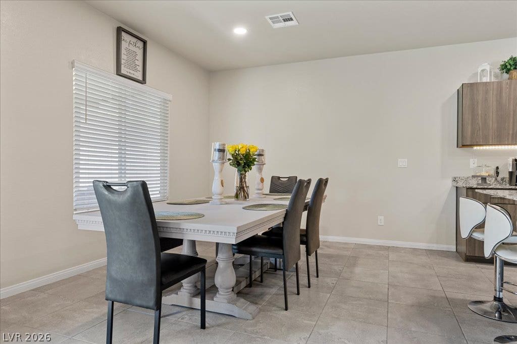 Natural light illuminates this spacious dining area with elegant tiled flooring.