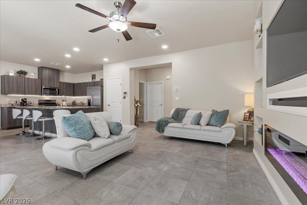 An open-concept living area boasts sleek tile flooring, integrating a modern kitchen and inviting lounge space.
