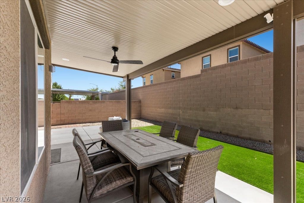 An inviting covered patio with a ceiling fan provides an ideal setting for outdoor dining and relaxation.