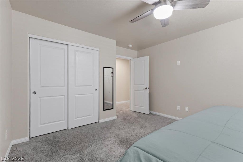 A comfortable bedroom features plush carpeting, a wide closet, and an inviting ceiling fan.