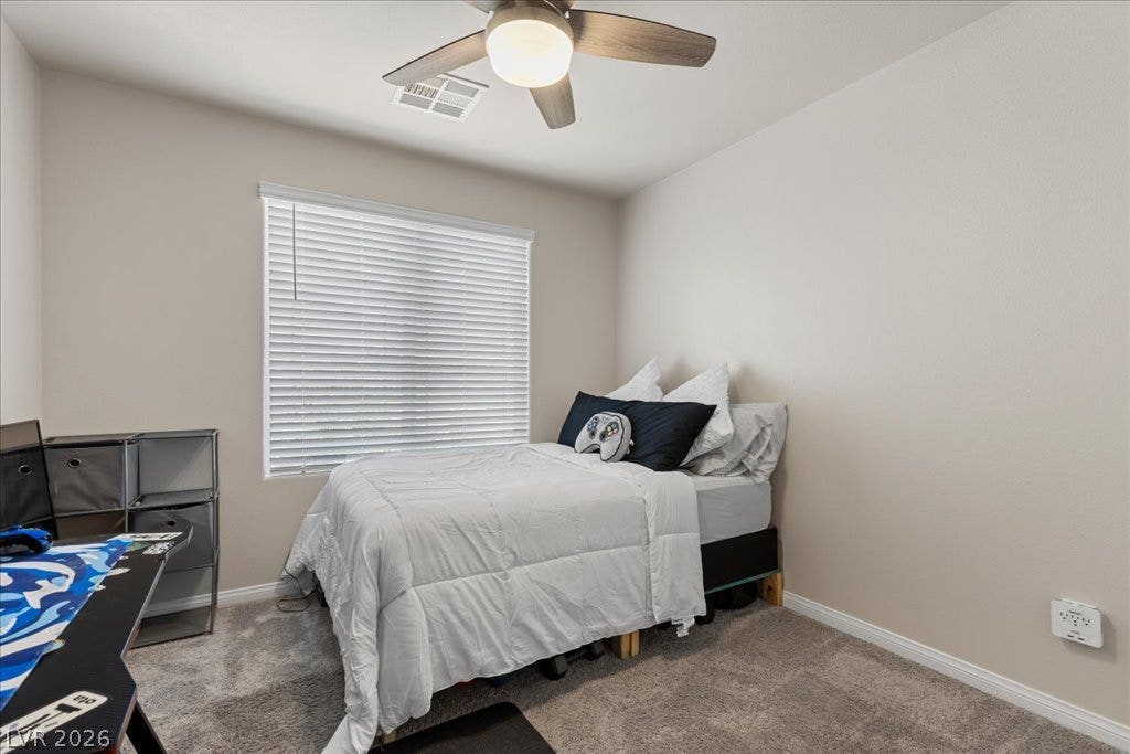 Well-appointed bedroom featuring a ceiling fan, plush carpeting, and abundant natural illumination.