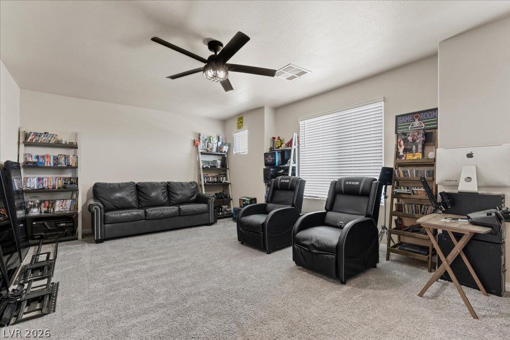 Unwind in this spacious recreation room, featuring plush carpeting and a modern ceiling fan for comfort.