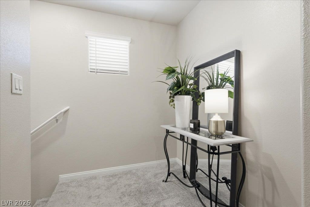 A well-lit landing area features a sleek console table and a neutral carpet, leading to a staircase.