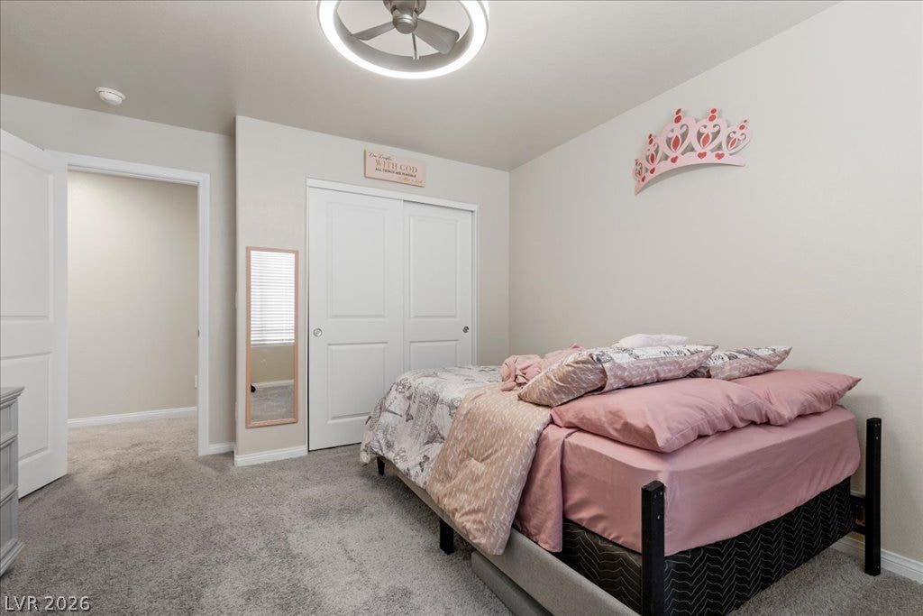 A well-appointed sleeping area boasts practical carpeted flooring and sliding closet doors.
