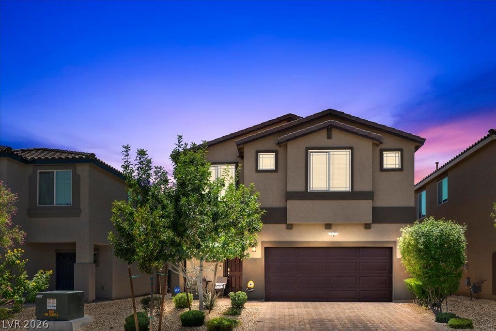 A well-maintained facade with an attached garage, showcasing attractive landscaping under a vibrant twilight sky.