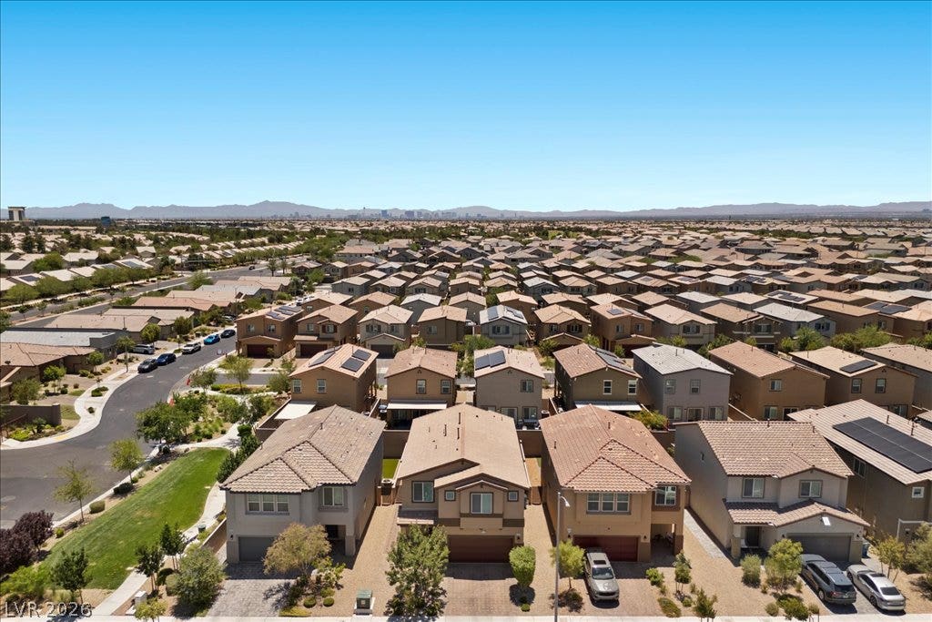 An aerial perspective reveals a vibrant community of homes under a bright desert sky, extending to distant mountains.