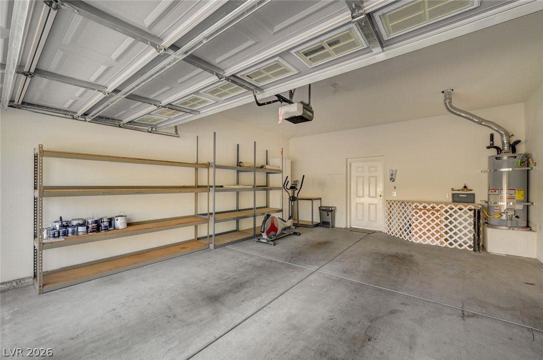 207 Kaelyn Street, #5, Boulder City, NV 89005 A spacious garage features durable concrete flooring, built-in shelving, and a sectional door with windows.