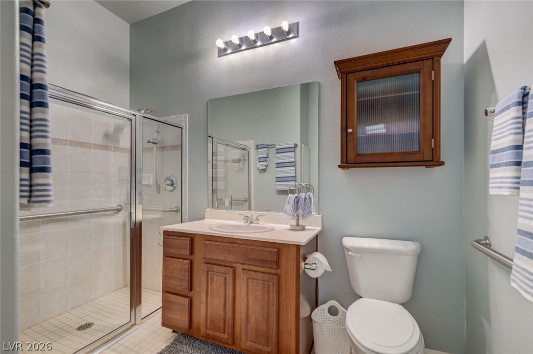 207 Kaelyn Street, #5, Boulder City, NV 89005 A well-appointed bathroom features a glass-enclosed walk-in shower and warm wood cabinetry.