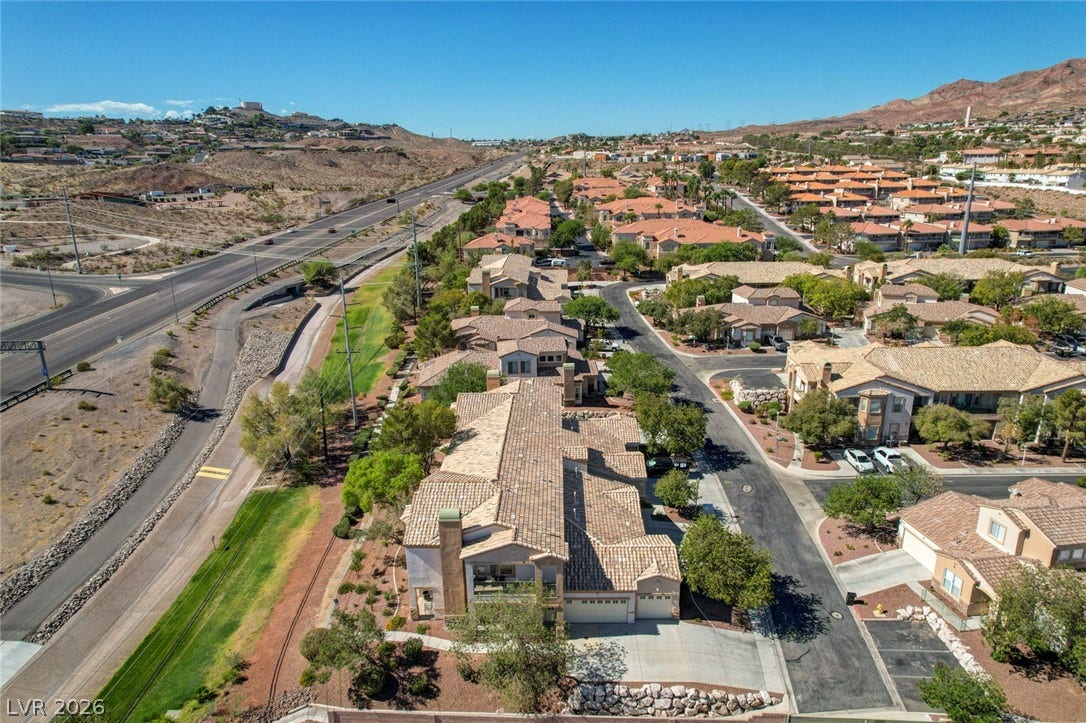 207 Kaelyn Street, #5, Boulder City, NV 89005 An aerial perspective reveals tile-roofed residences nestled alongside scenic desert hillsides.