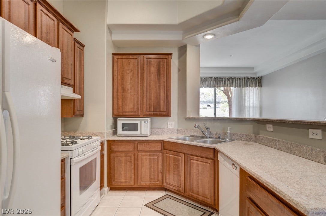 207 Kaelyn Street, #5, Boulder City, NV 89005 Rich wood cabinetry and stone counters define this kitchen overlooking the main living area.