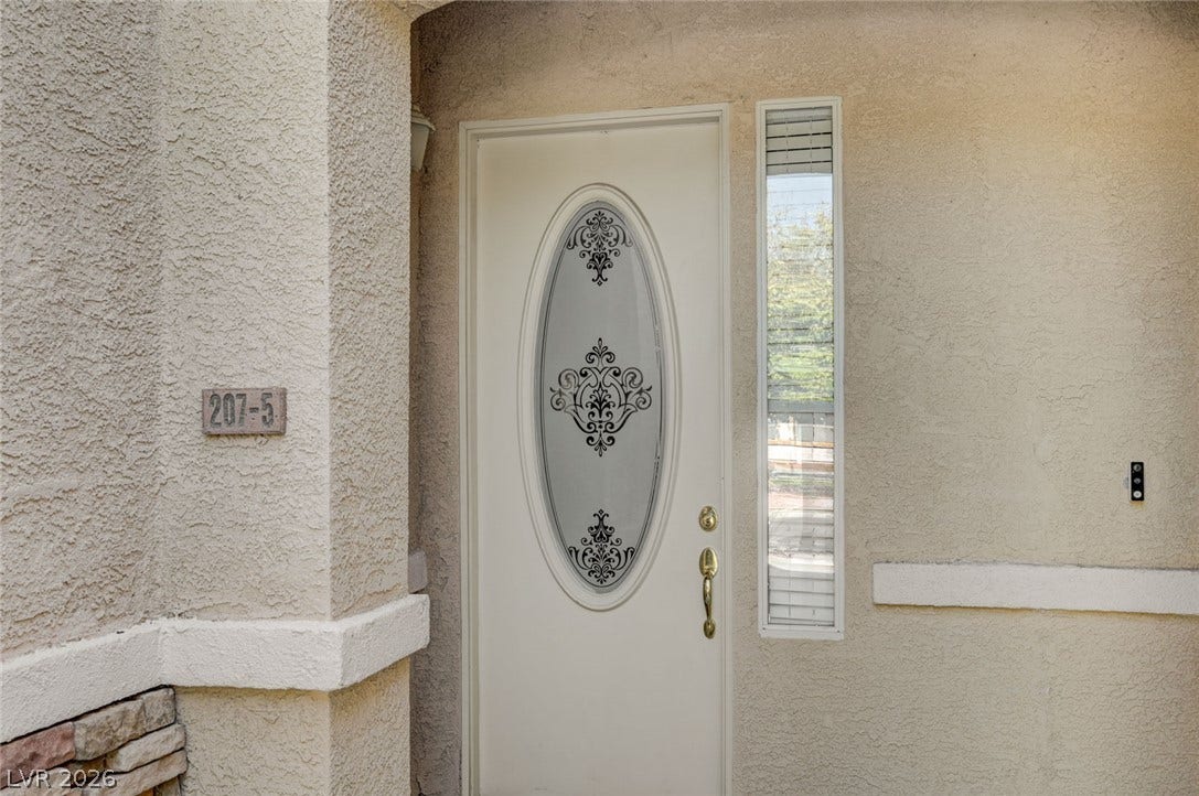 207 Kaelyn Street, #5, Boulder City, NV 89005 An inviting front entry welcomes visitors with textured stucco walls and decorative glass detailing.