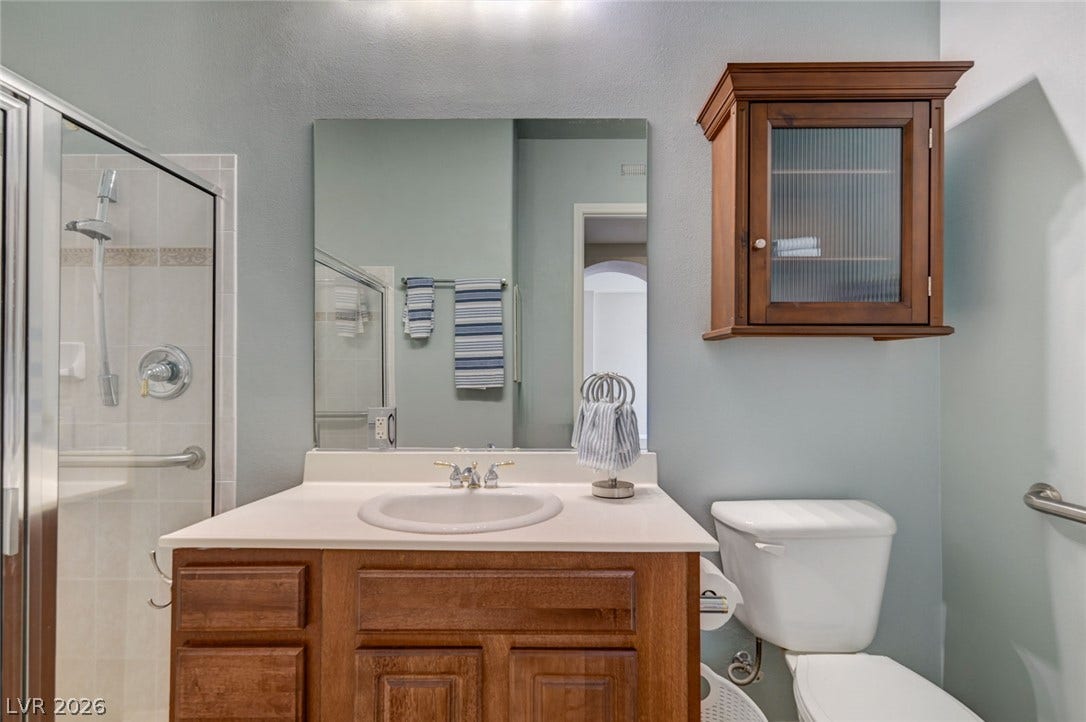 207 Kaelyn Street, #5, Boulder City, NV 89005 An elegant wooden vanity sits adjacent to a glass-doored walk-in shower.