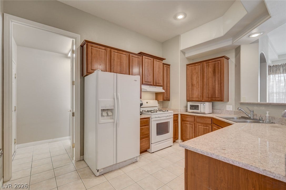 207 Kaelyn Street, #5, Boulder City, NV 89005 Rich wood cabinetry pairs beautifully with expansive stone countertops in this functional kitchen.