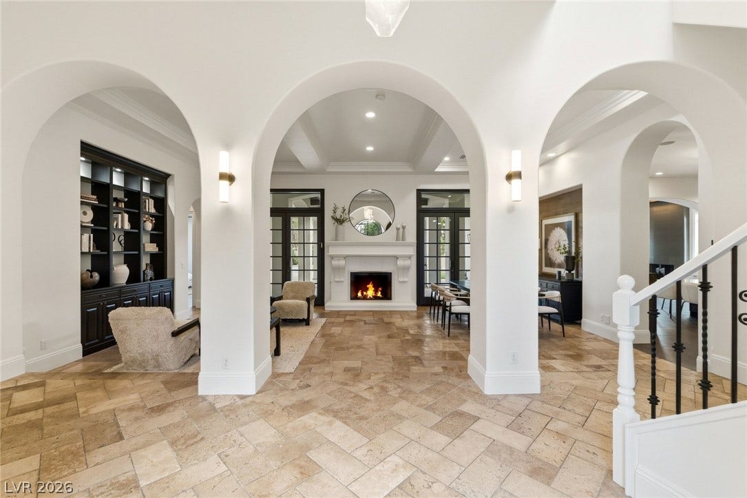 Graceful archways frame a view of the fireplace and elegant stone flooring.