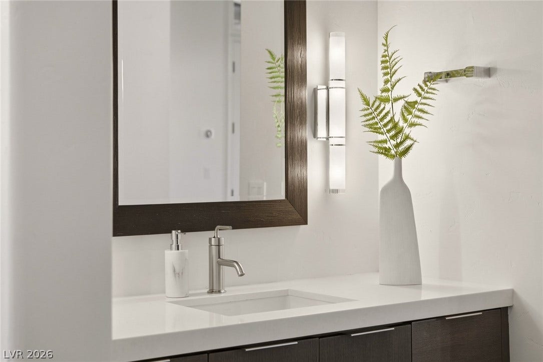A sleek modern vanity features a crisp under-mount sink paired with a dark-framed mirror.