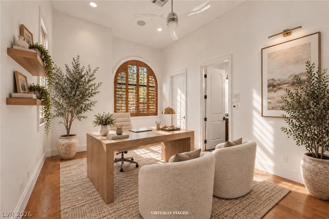 Rich hardwood floors and an arched window highlight this refined home office workspace.
