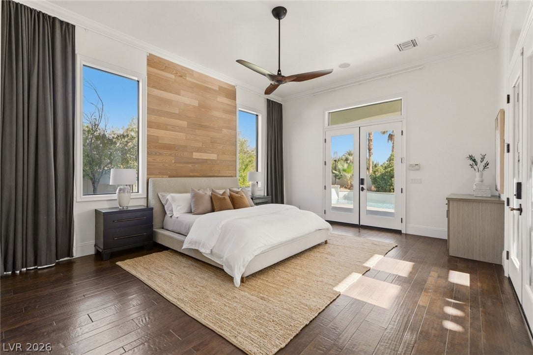 Gleaming hardwood floors and a wood-paneled accent wall define this serene bedroom space.