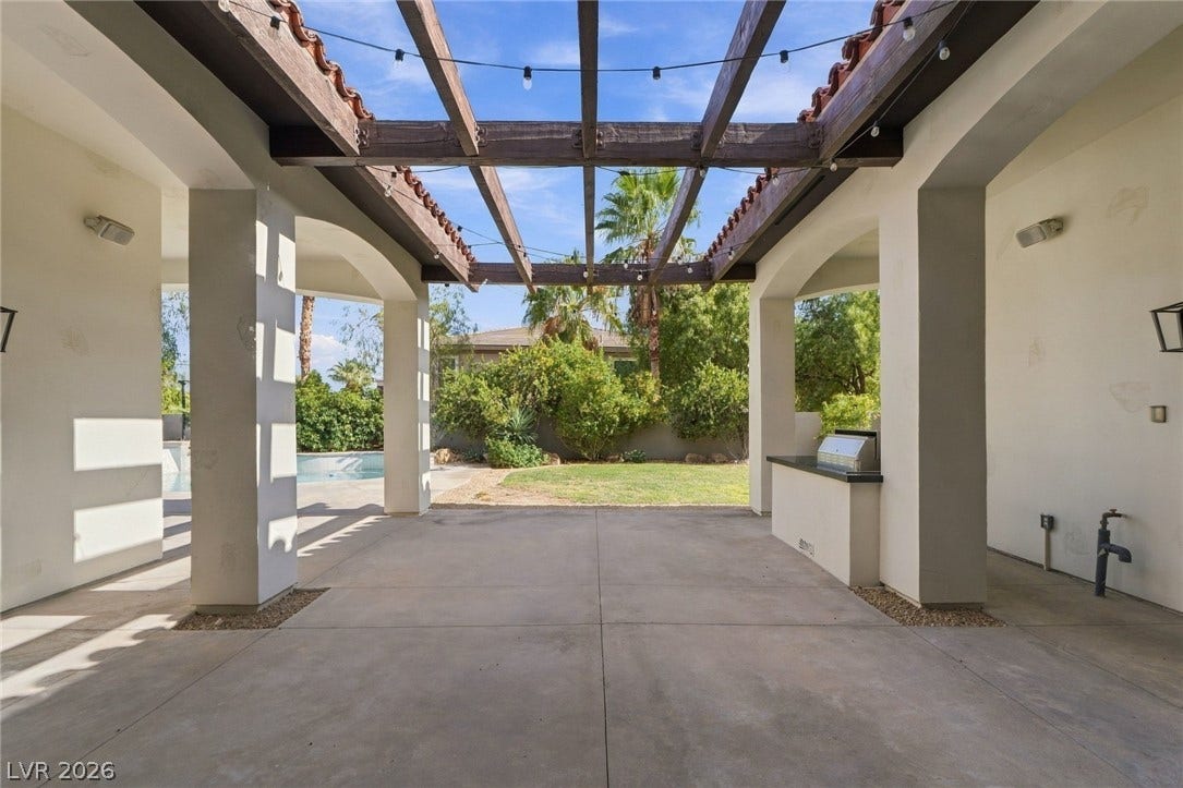 A spacious covered patio features an open timber trellis overlooking the pool and grassy yard.