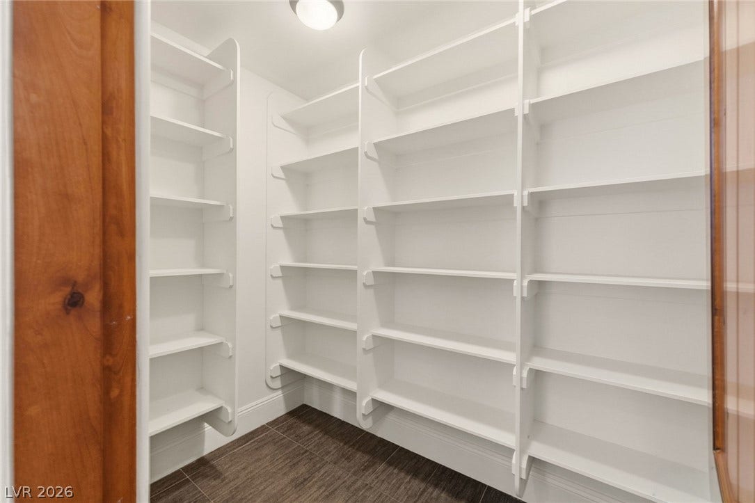 Floor-to-ceiling built-in shelving maximizes storage space within this walk-in pantry.