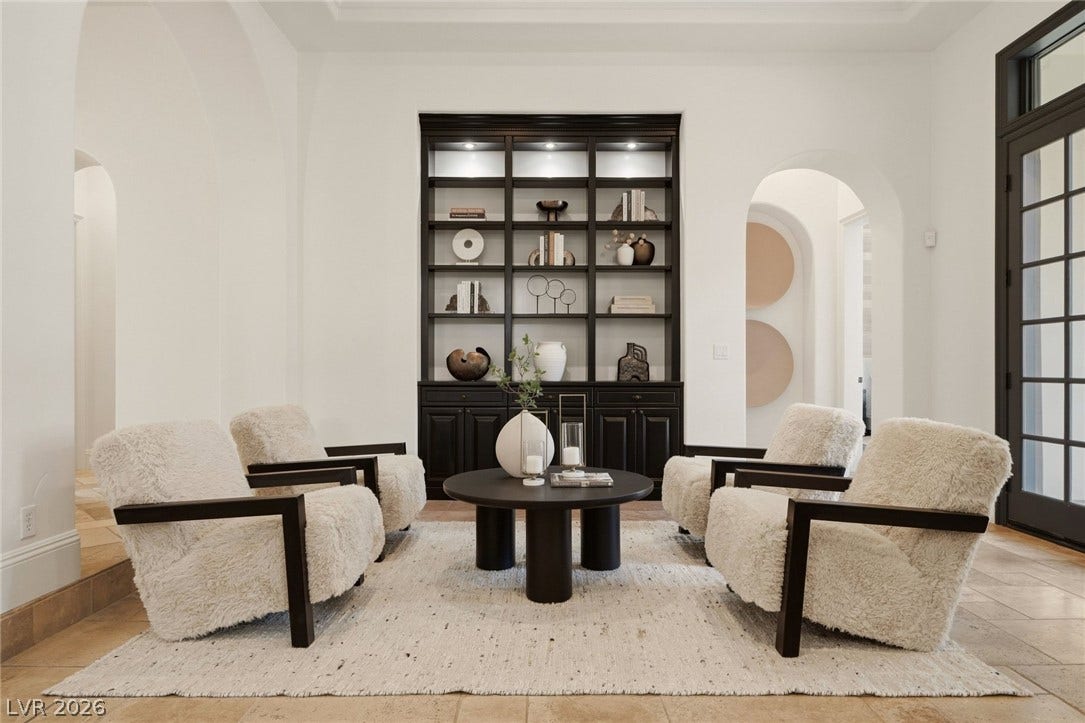Arched doorways and a custom dark wood bookcase define this elegant sitting area.