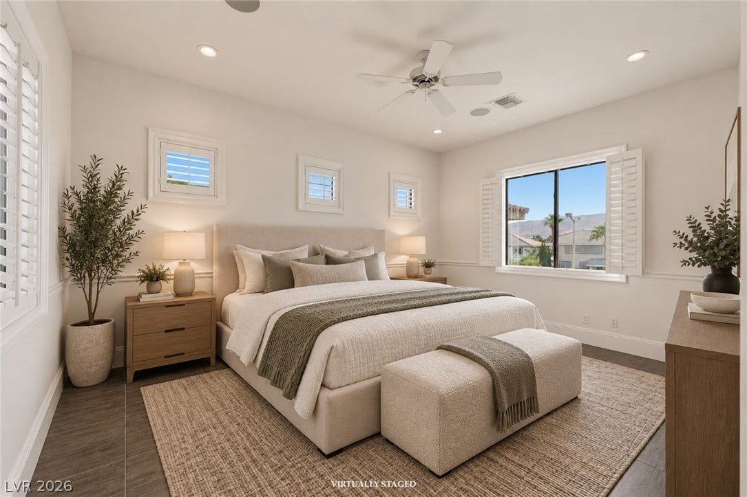 Recessed lighting and plantation shutters frame a relaxing bedroom retreat with wood-look flooring.