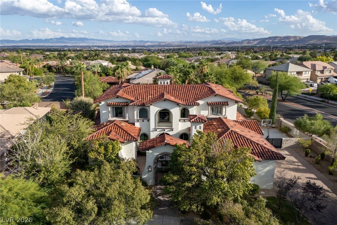 Distinguished Mediterranean estate with Spanish tile roofing showcases sweeping neighborhood and mountain views.