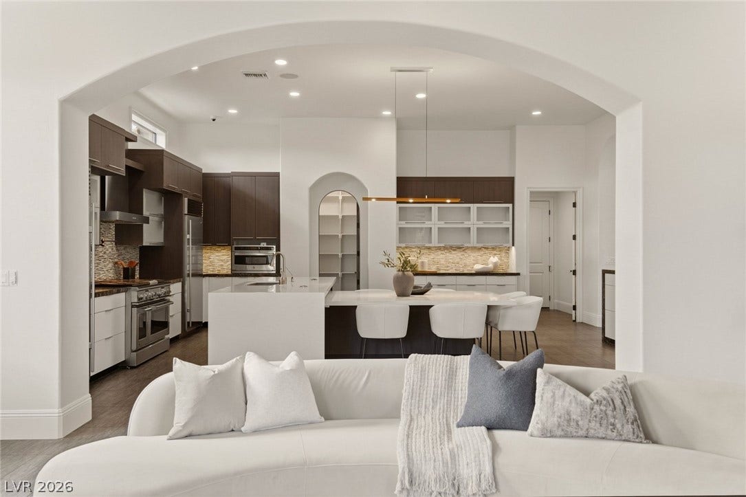 An elegant arched entryway reveals a seamless flow into a modern, open-concept kitchen.