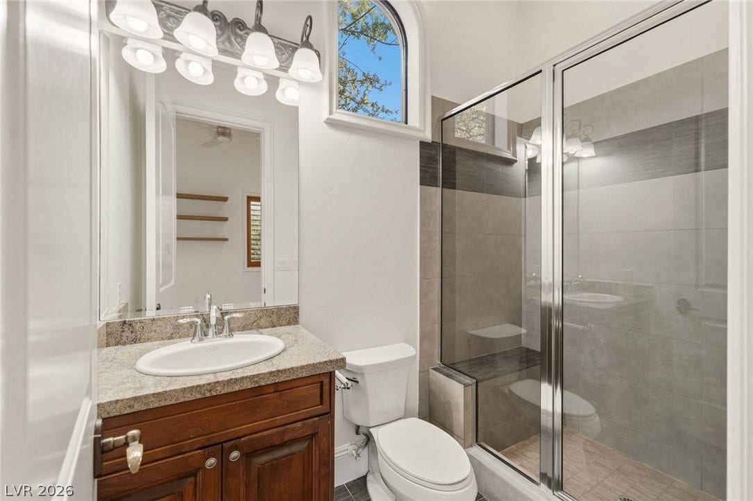 Gleaming stone countertops and a modern glass shower elevate this refined bathroom space.