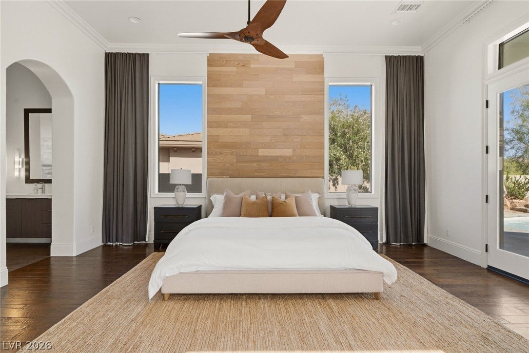 Rich hardwood flooring and crown molding frame a master suite opening directly to the outdoors.