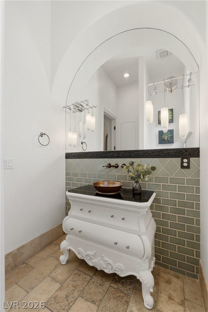 An arched mirror and tiled backsplash accent this charming powder room.