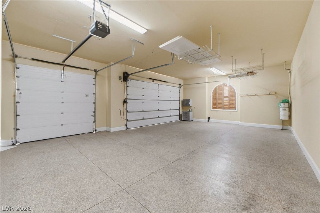 An immaculate three-car garage features durable epoxy flooring and overhead storage racks.