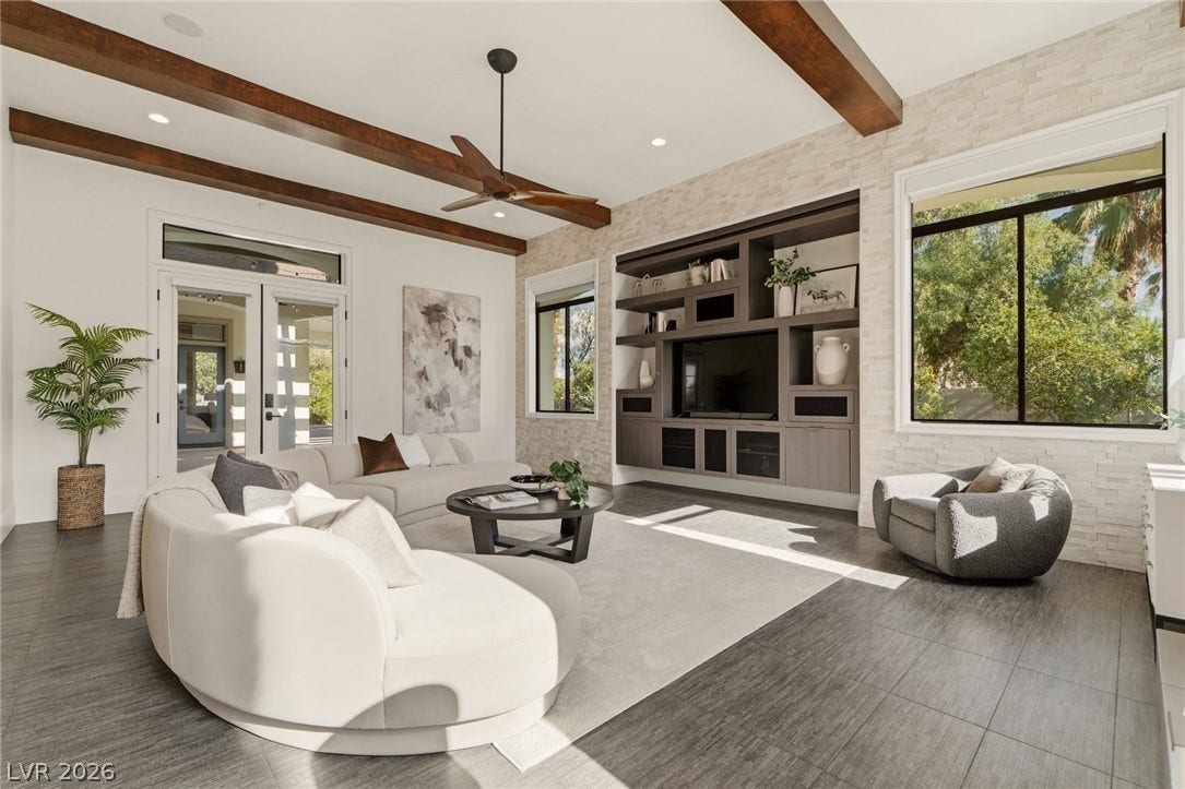 Rich wood ceiling beams and custom built-in cabinetry elevate this airy living space.