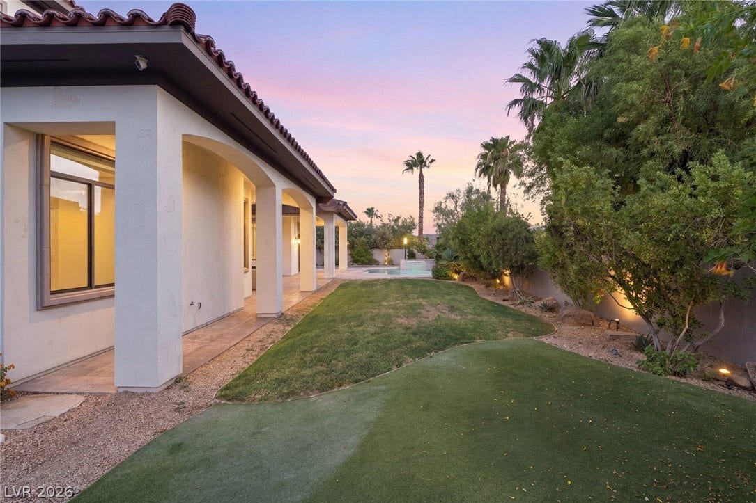 Mediterranean architectural detailing frames a manicured lawn flanked by lush desert plantings.
