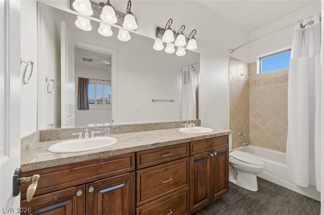 Rich wood cabinetry and stone countertops elevate this modern bathroom space.