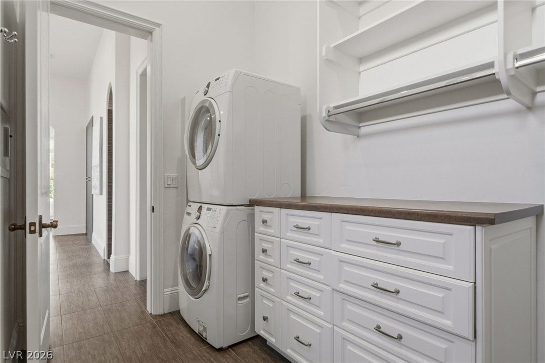 A functional laundry space highlights custom cabinetry, rich wood countertops, and modern wood-look tile flooring.