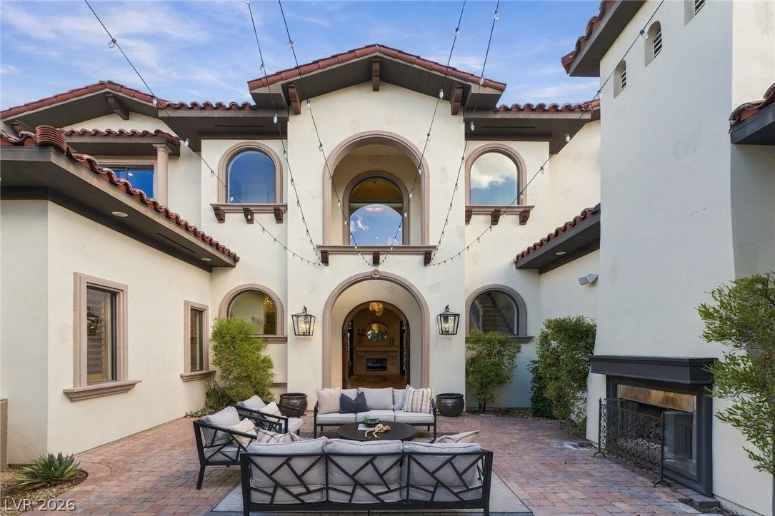 An inviting courtyard features warm paver flooring below elegant Mediterranean architectural details.