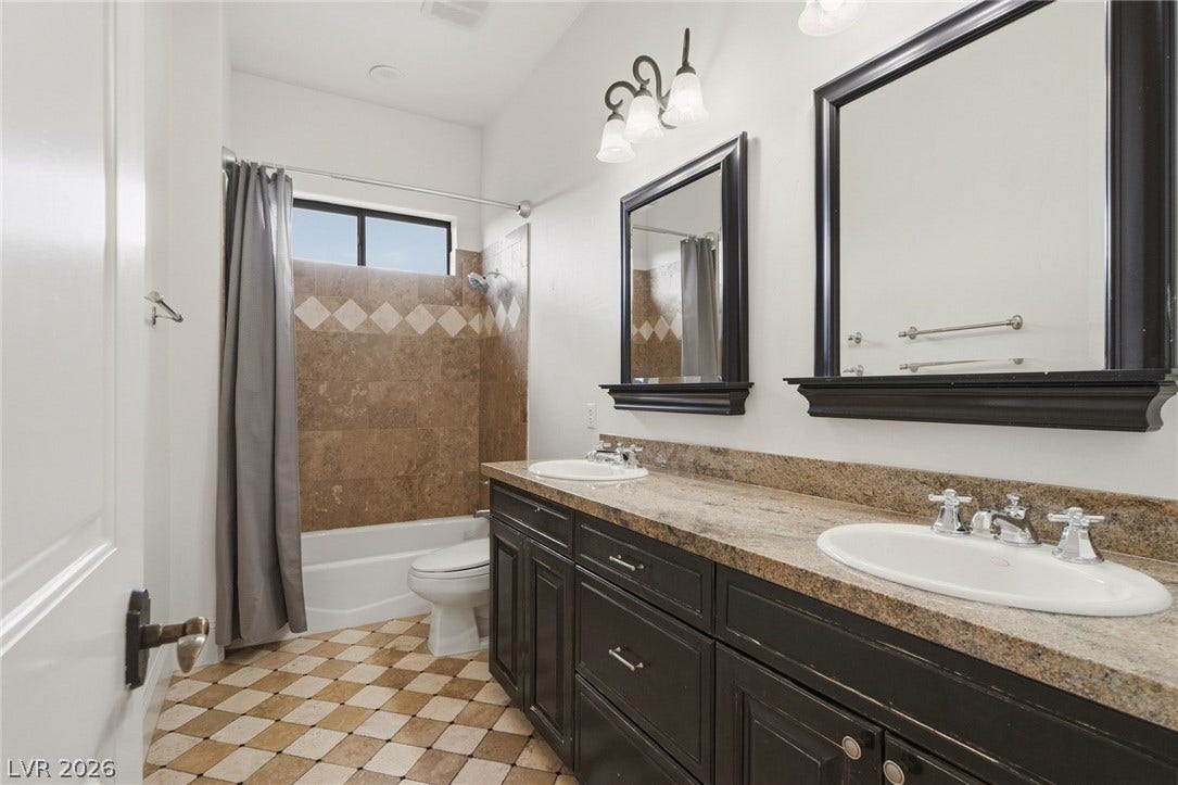 Granite counters and a dual vanity elevate this spacious bath with tiled flooring.