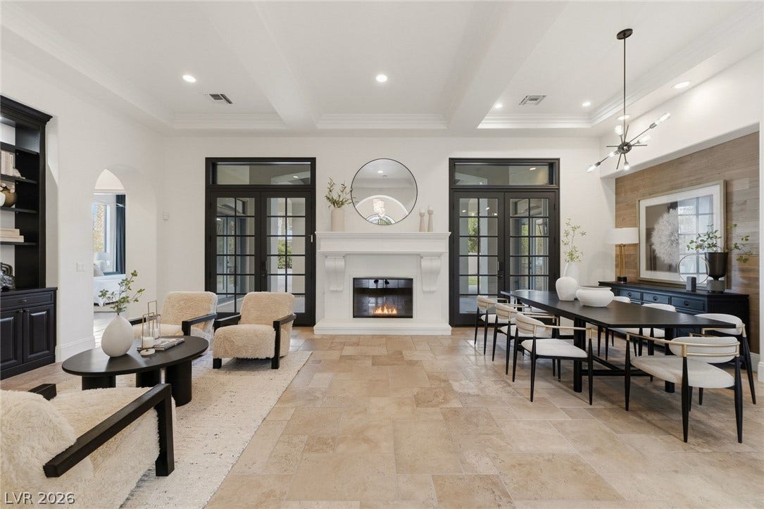 Stone tile flooring and coffered ceilings elevate this open living and dining space.