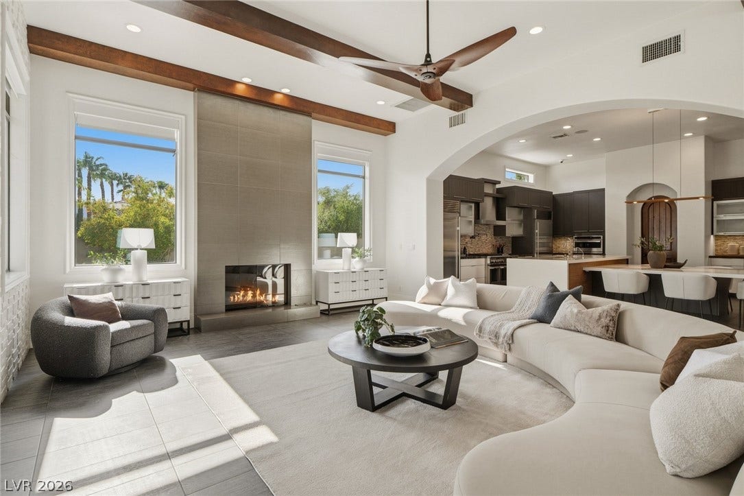 Exposed wood beams and a sleek modern fireplace define this open living space.