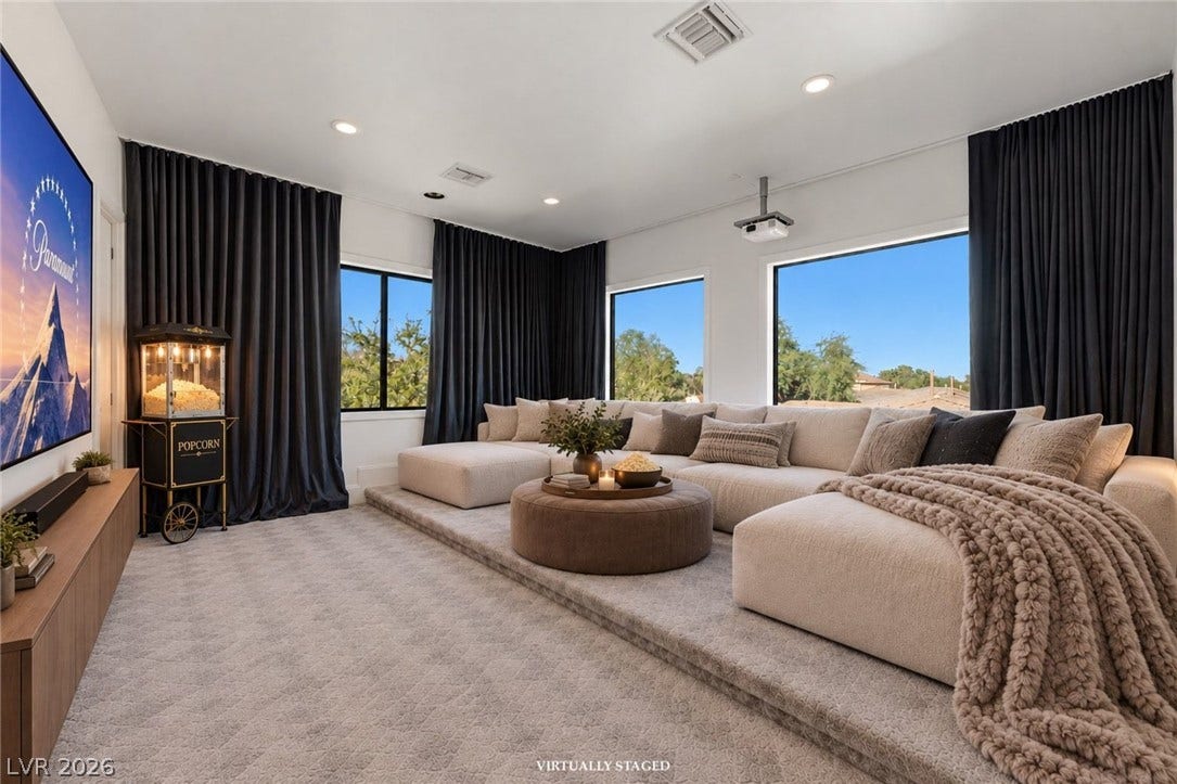 A spacious home theater features plush wall-to-wall carpeting and large windows framing exterior views.