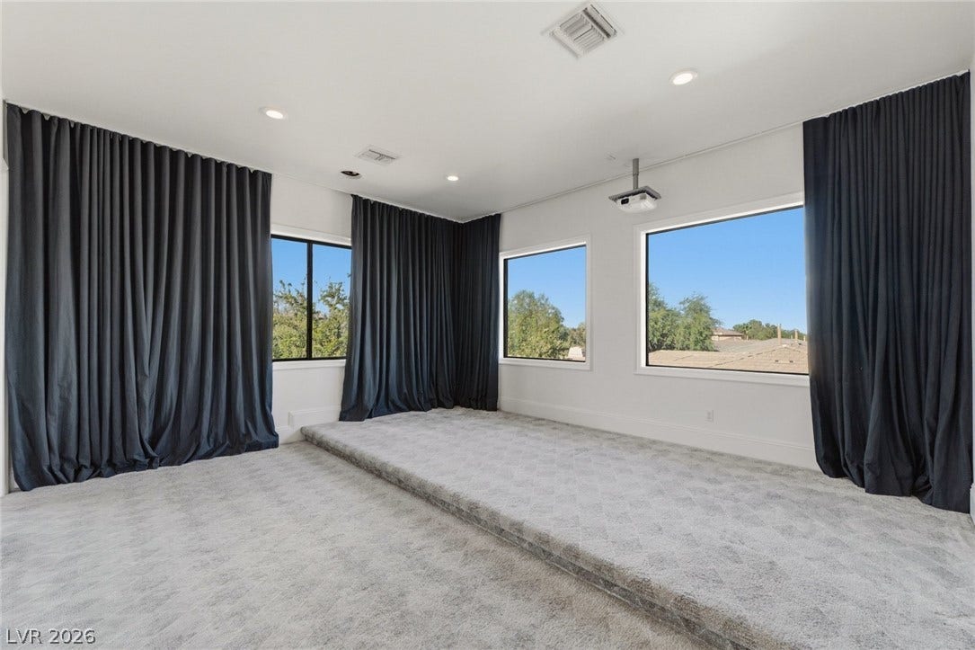 A raised platform structure anchors this media room featuring large picture windows and recessed lighting.
