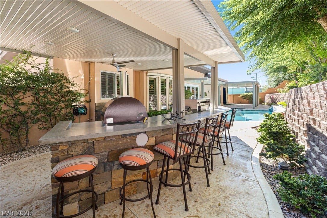 1517 Marbella Ridge Court, Las Vegas, NV 89117 An inviting stone-accented outdoor kitchen bar overlooks the sparkling backyard swimming pool.