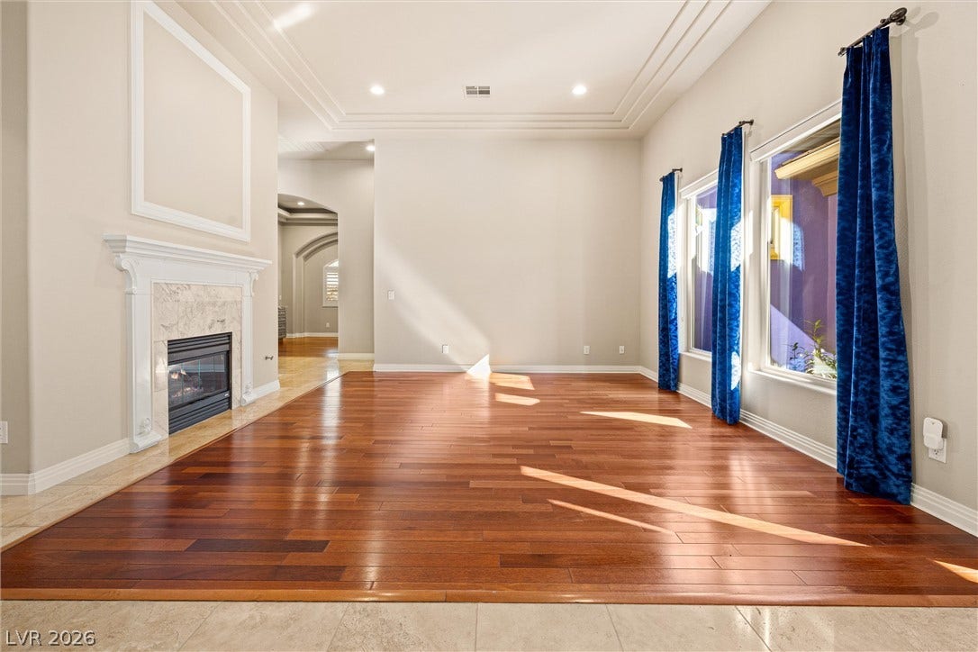 1517 Marbella Ridge Court, Las Vegas, NV 89117 Polished hardwood floors and a classic fireplace anchor this light-filled room with high tray ceilings.