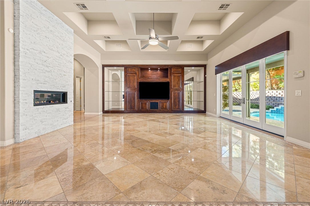 1517 Marbella Ridge Court, Las Vegas, NV 89117 Polished stone flooring, a soaring coffered ceiling, and a sleek stone fireplace define this space.