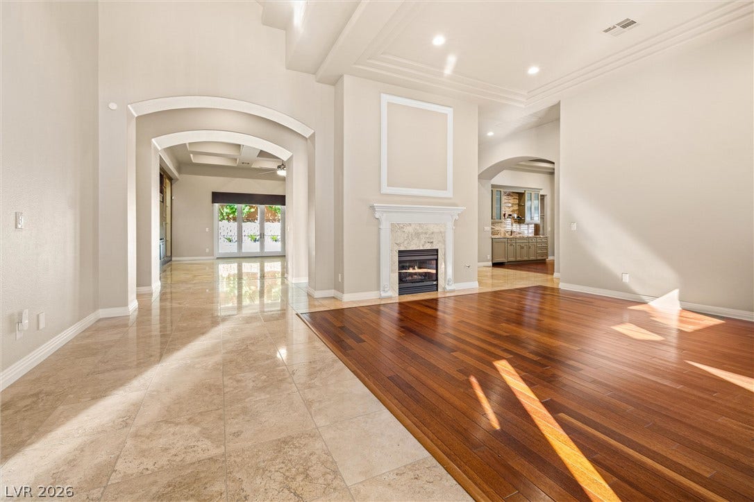 1517 Marbella Ridge Court, Las Vegas, NV 89117 Polished stone and warm wood flooring frame a light-filled living area featuring a classic fireplace.
