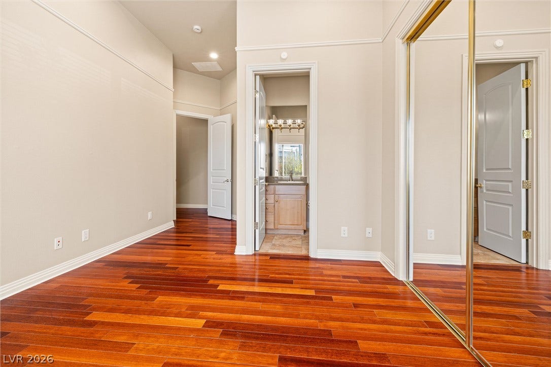 1517 Marbella Ridge Court, Las Vegas, NV 89117 Gleaming hardwood floors and high ceilings define this versatile bedroom space with mirrored closet doors.