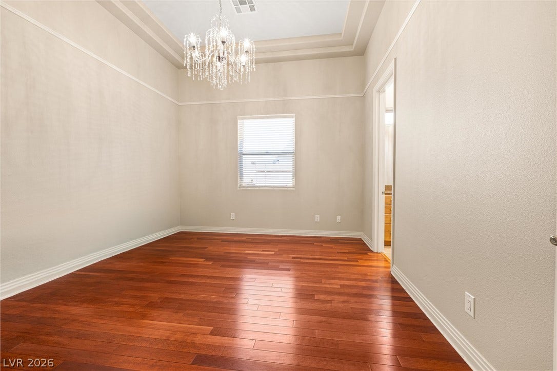 1517 Marbella Ridge Court, Las Vegas, NV 89117 Warm hardwood flooring and a tray ceiling with a crystal chandelier define this versatile space.