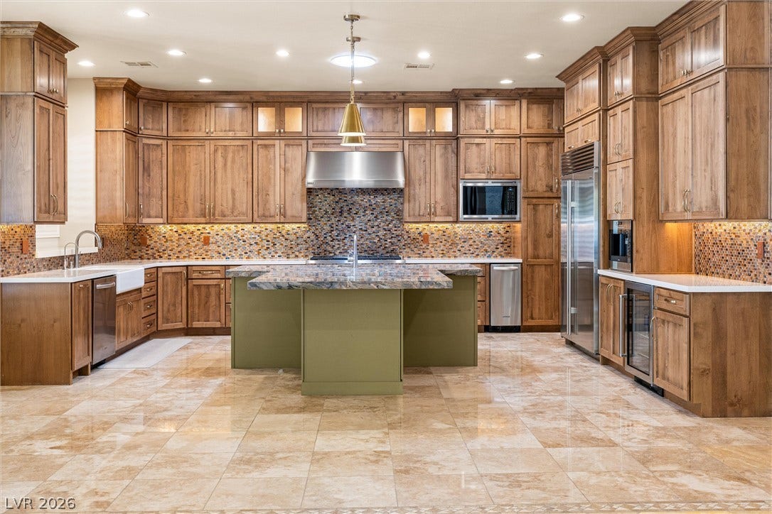 1517 Marbella Ridge Court, Las Vegas, NV 89117 Gleaming tile floors and expansive wooden cabinetry anchor this chef's kitchen centered around a stone-topped island.