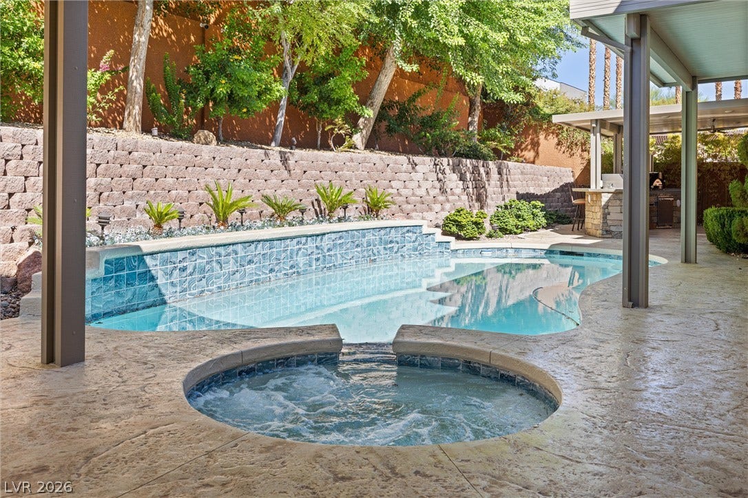 1517 Marbella Ridge Court, Las Vegas, NV 89117 An inviting swimming pool and integrated spa sit surrounded by textured decking and tiered masonry walls.